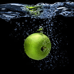 Image showing green apple dropped into water with splash isolated on black