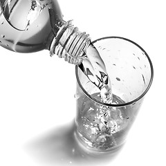 Image showing water pouring into glass from bottle isolated on white