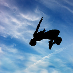 Image showing silhouette of jumping man against blue sky and clouds