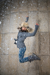 Image showing young woman jumping in fur hat against the wall