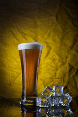 Image showing Beer in glass with ice cubes on yellow background