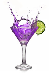 Image showing Violet alcohol cocktail with splash and green lime isolated on w