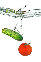 Image showing red tomato and green cucumber dropped into water isolated on whi