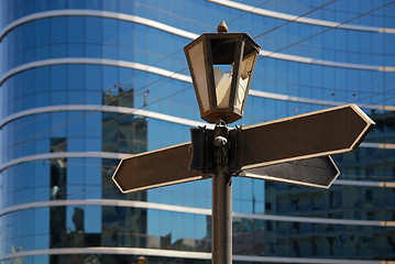 Image showing Blank signpost with ancient lamp against business building