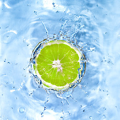 Image showing Fresh lime dropped into water with bubbles isolated on white