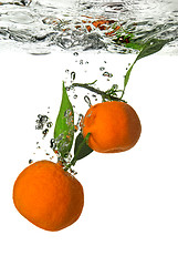 Image showing tangerine dropped into water with bubbles on white