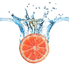 Image showing Fresh grapefruit dropped into water with bubbles isolated on whi