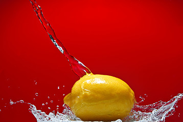 Image showing Fresh lemon and water splash on red