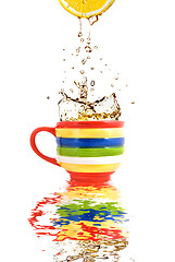 Image showing Lemon juice and splash of tea in color cup with reflection