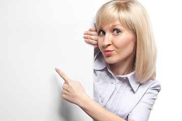 Image showing Attractive smiling woman holding white empty paper and pointing 