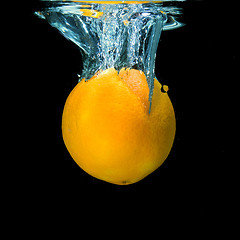 Image showing orange dropped into water on black