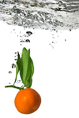 Image showing tangerine dropped into water with bubbles on white