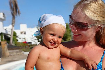 Image showing portrait of smilling mother and daughter near pool. Focus on the