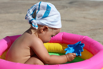 Image showing baby girl playing in a colorful kiddie pool