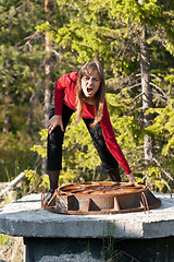 Image showing Woman tries to lift rusty manhole