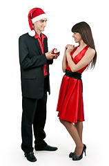 Image showing Man in Santa hat gives a woman a ring