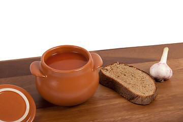 Image showing Soup in clay pot on wooden table