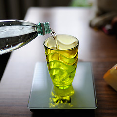 Image showing Bottle pouring water into a glass against kitchen background