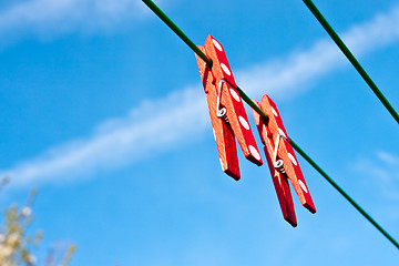 Image showing Two red clothes pegs against a bright blue sky