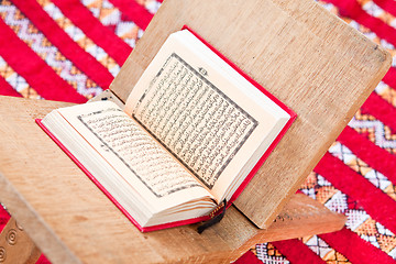 Image showing Warsh quran open on a wooden stand on a red Moroccan rug