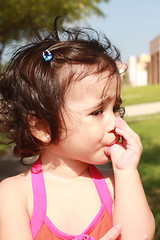 Image showing Little baby girl, sucking her thumb walking in the park