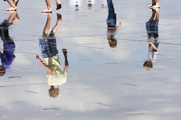 Image showing Reflections of teens walking in the water.