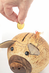 Image showing Saving, male hand putting a coin into piggy bank. 