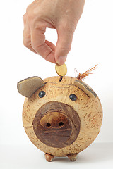 Image showing Saving, male hand putting a coin into piggy bank. 