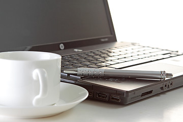 Image showing A cup of coffee and a pen on a laptop 