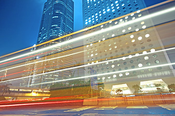 Image showing traffic light trails in the street by modern building