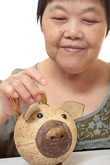 Image showing woman putting coins in small piggy bank. Selective focus, Copy s