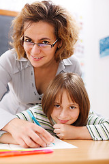 Image showing Teacher helping schoolgirl writing