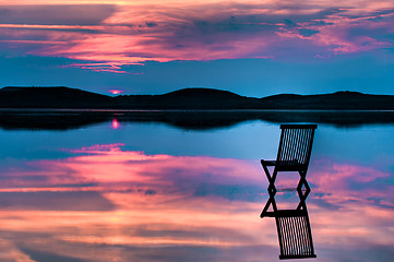 Image showing Scenic view of sunset over inlet and hills with a chair in the c