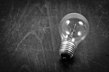 Image showing Light bulb on wooden plate in black and white