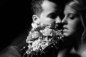 Image showing young couple in wedding wear with bouquet of roses 