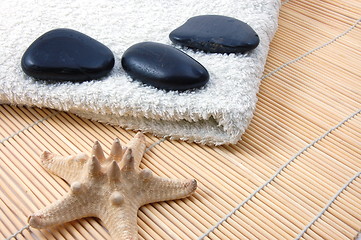 Image showing foldet white bath towel and zen stones