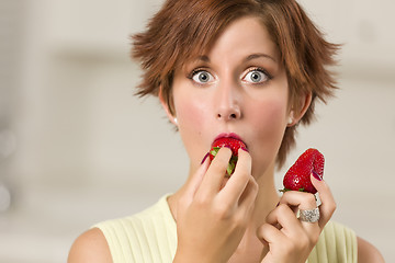 Image showing Pretty Wide-eyed Red Haired Woman Biting Strawberry