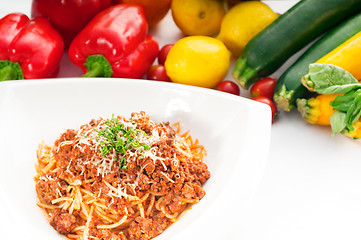 Image showing spaghetti with bolognese sauce and fresh vegetables on backgroun