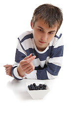 Image showing Boy inspecting blueberry