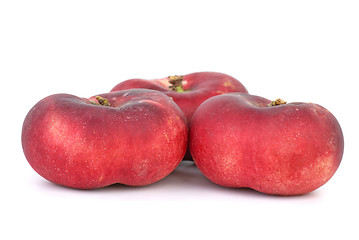 Image showing Three red flat peaches