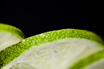 Image showing Slices of lime fruit on black