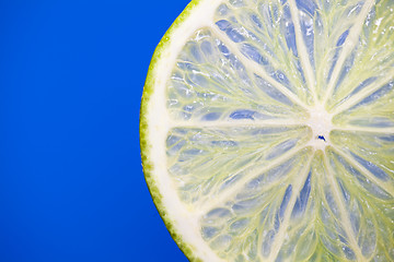 Image showing A single slice of lime on blue