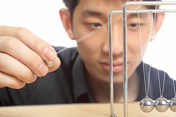 Image showing man moving Newton balls in office 