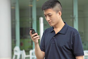 Image showing Asian man typing a message on mobile phone.