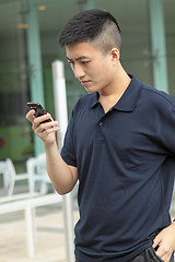 Image showing Asian man typing a message on mobile phone.