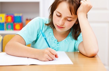 Image showing Schoolgirl writing boring homework