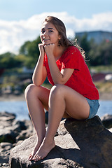 Image showing girl in a red sweater sits on a rock