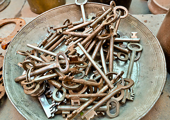 Image showing a lot of old brass key on an old plate