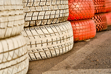 Image showing close up of racetrack fence of white and red of old tires