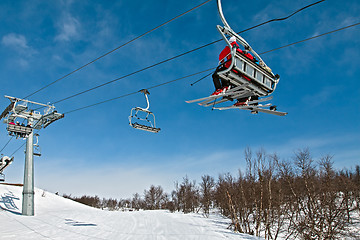Image showing Chair lift with skiers on a blue sky